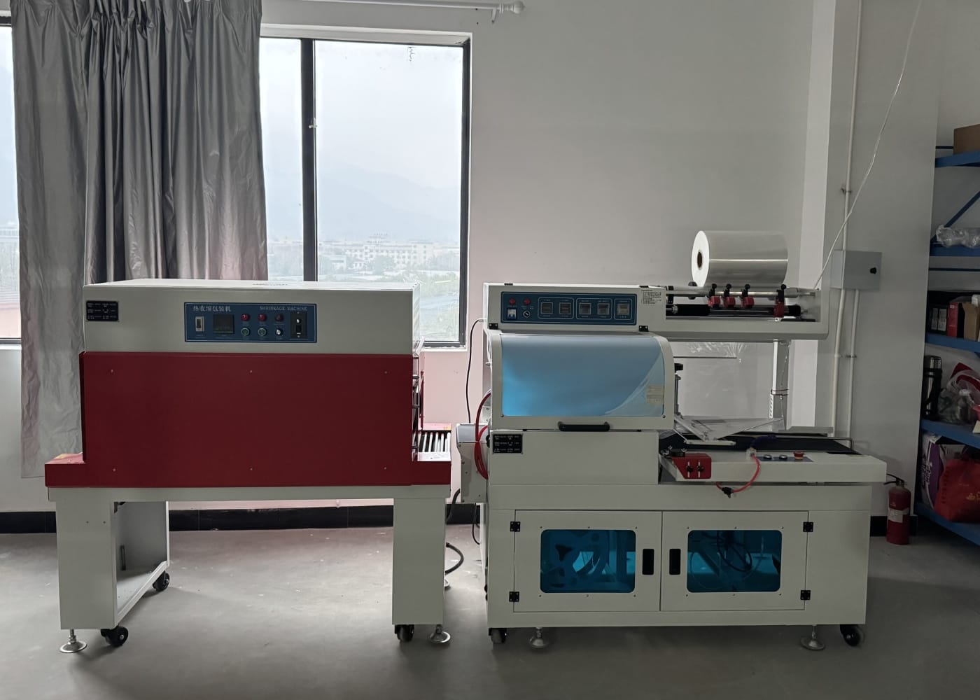 Two industrial shrink wrap machines in a factory setting.