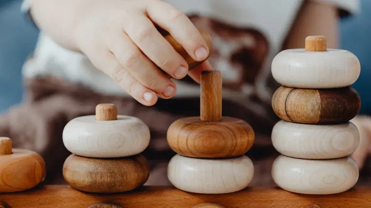 Mains d'enfant empilant des anneaux en bois, jouets éducatifs en bois.