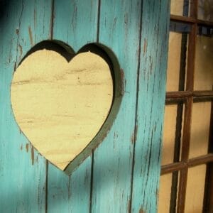 Découpe en forme de cœur dans une porte en bois bleu sarcelle patiné
