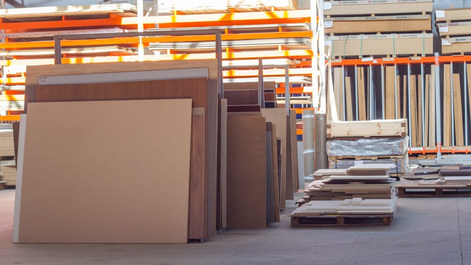 Différents panneaux de bois empilés dans un entrepôt avec des étagères et des palettes. Types de Bois