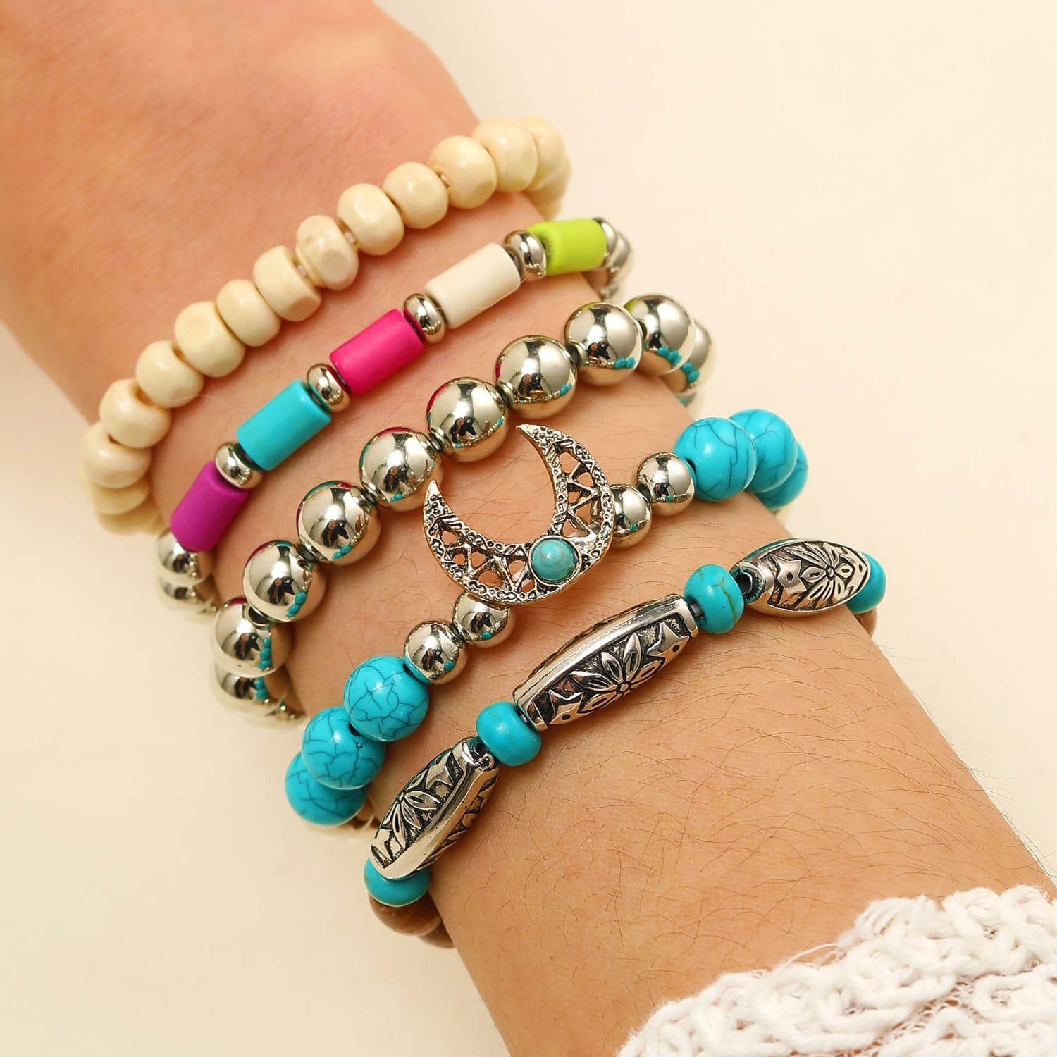 Poignet de femme orné de bracelets superposés en turquoise, en perles et bracelet en bois.