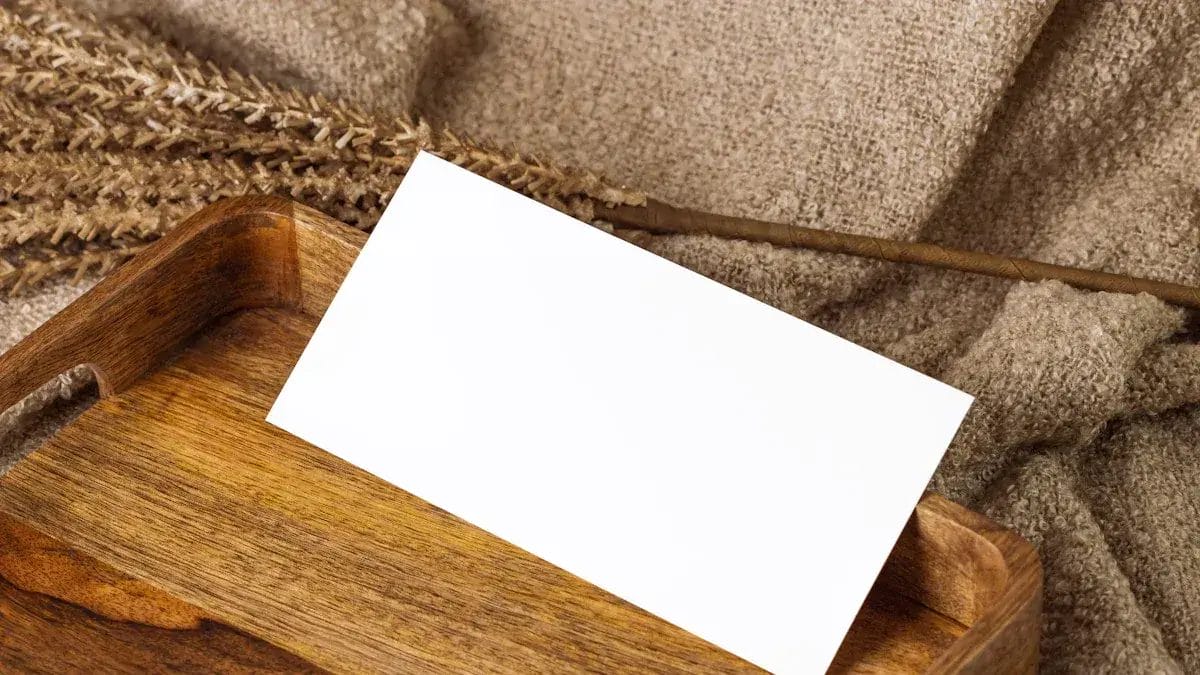 Carte blanche vierge dans un plateau en bois sur tissu texturé.