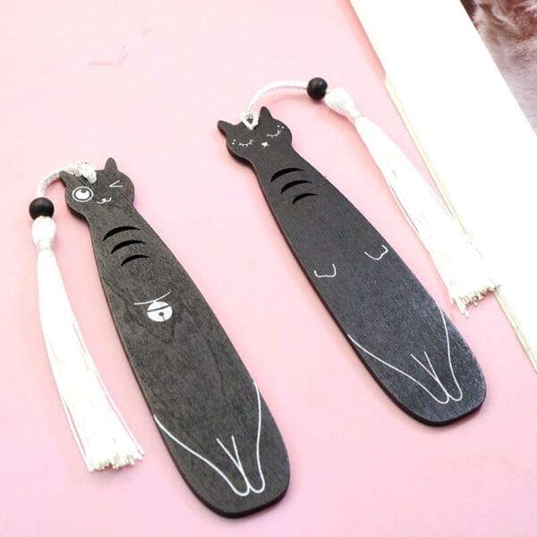 Deux adorables marque-pages en bois noir en forme de chat avec pompons blancs. Vente en gros.