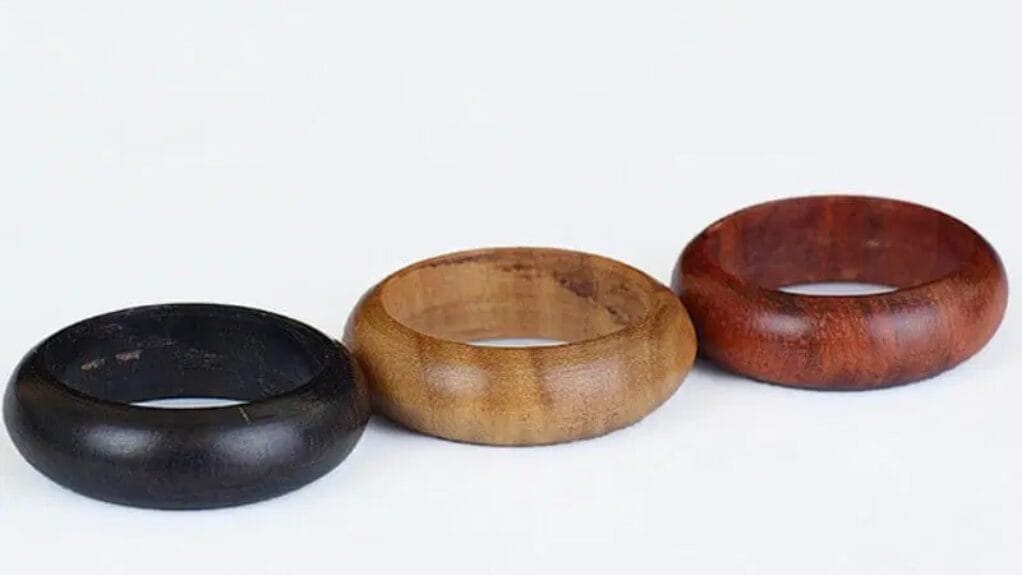 Trois bagues en bois de différentes couleurs sur fond blanc.