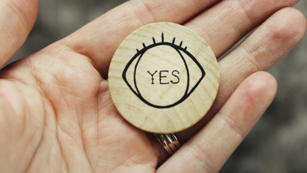 Comment faire des badges en bois : Badge en bois rond avec œil stylisé et le mot "YES